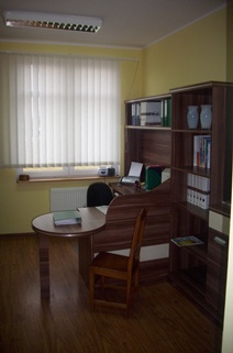 Sekretariat, okno, brązowe szafki, biurko, krzesło